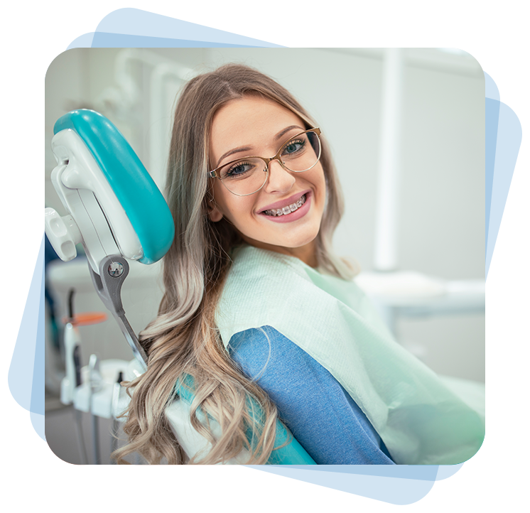 Woman with braces and glasses smiling in a dental chair.