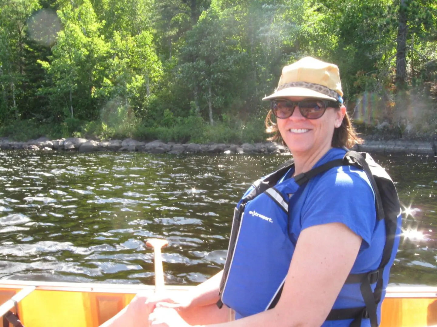 A woman in blue shirt and hat on boat.