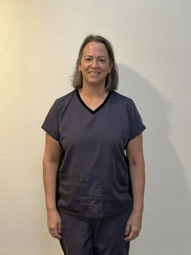 A woman standing in front of a white wall.