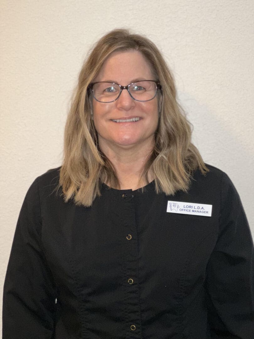 A woman in black shirt and glasses smiling for the camera.